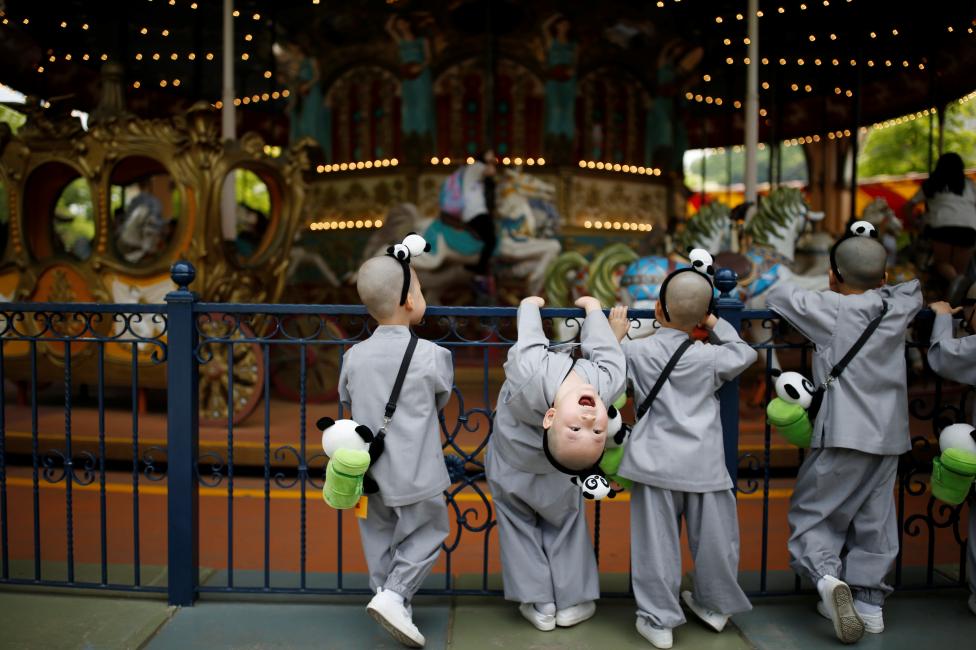 Boys, who are experiencing the lives of Buddhist monks by staying in a temple for two weeks as novice monks, look at a carousel at the Everland amusement park in Yongin, South Korea, May 9, 2016. REUTERS/Kim Hong-Ji